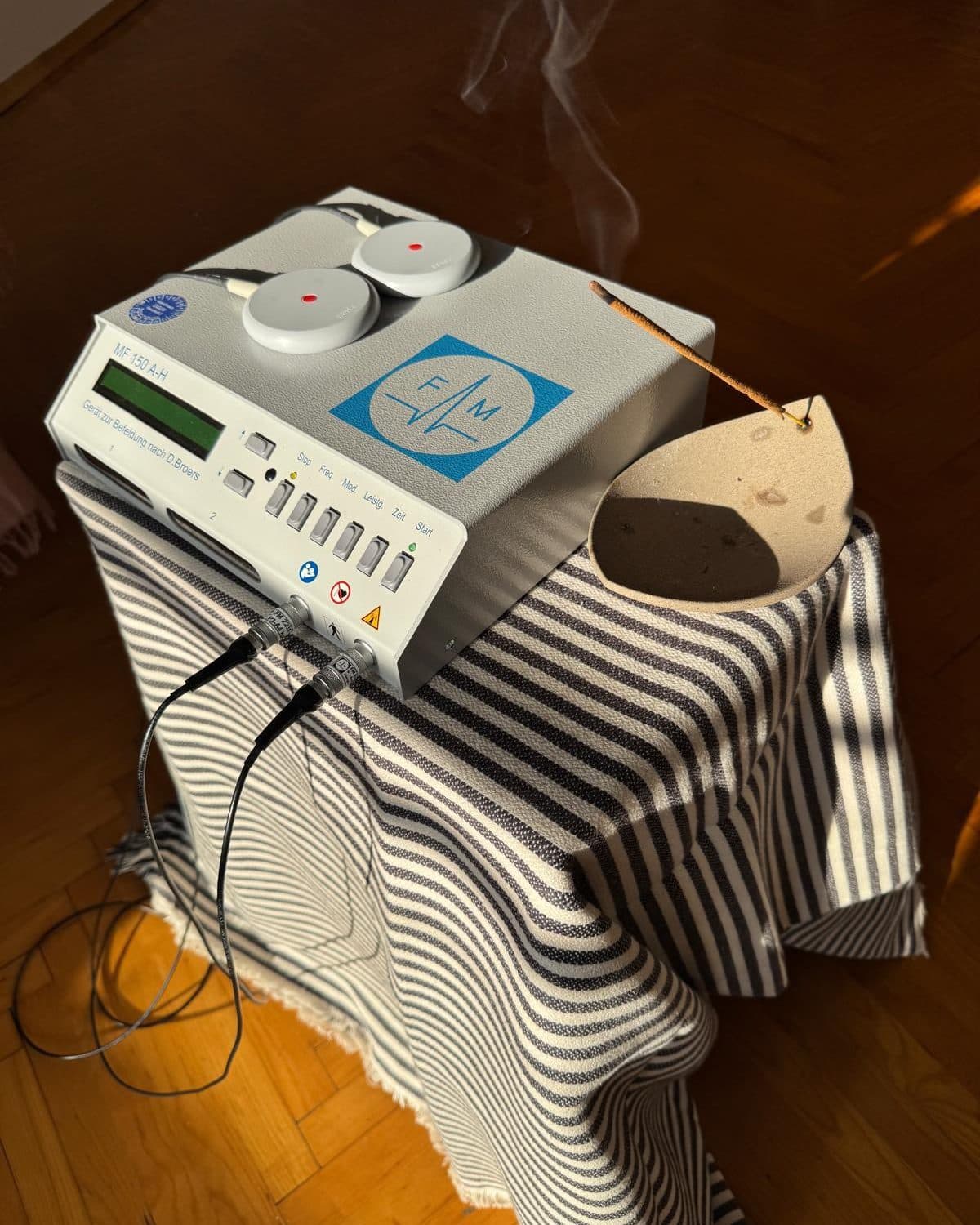 The frequency device used in sessions, with a stick of incense