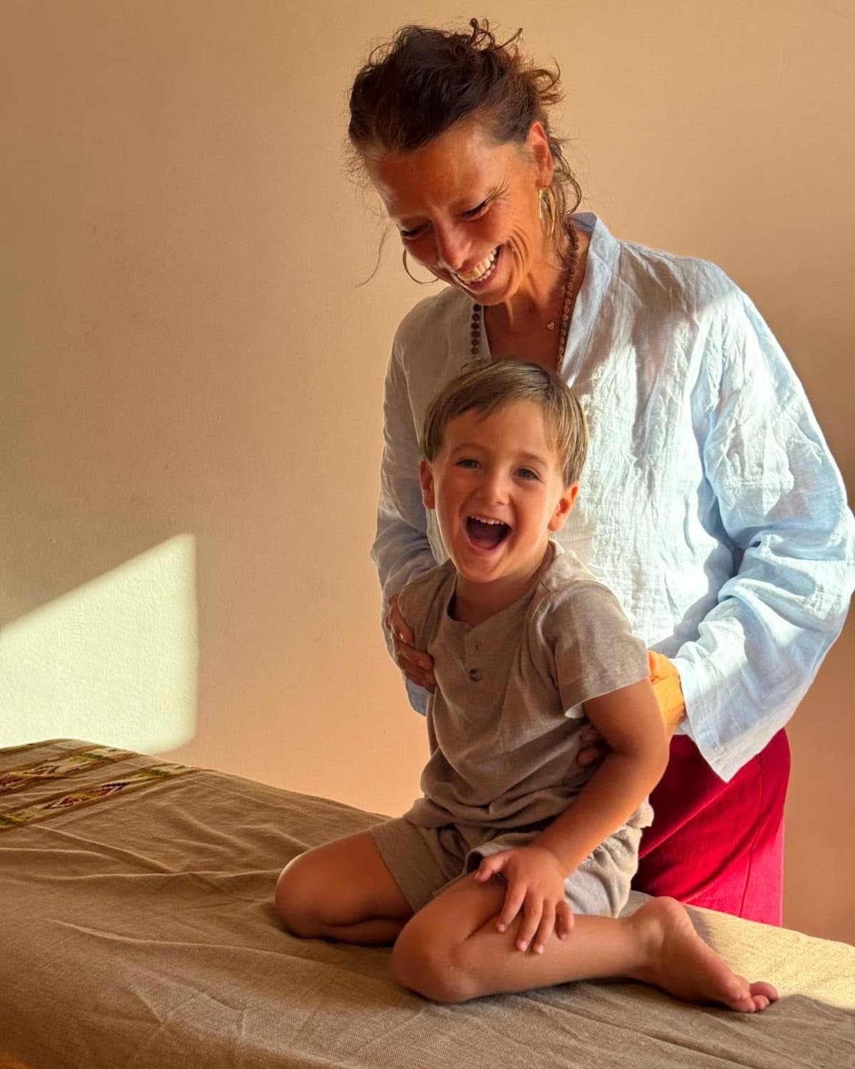 A laughing child sitting on the treatment table with Beatrix