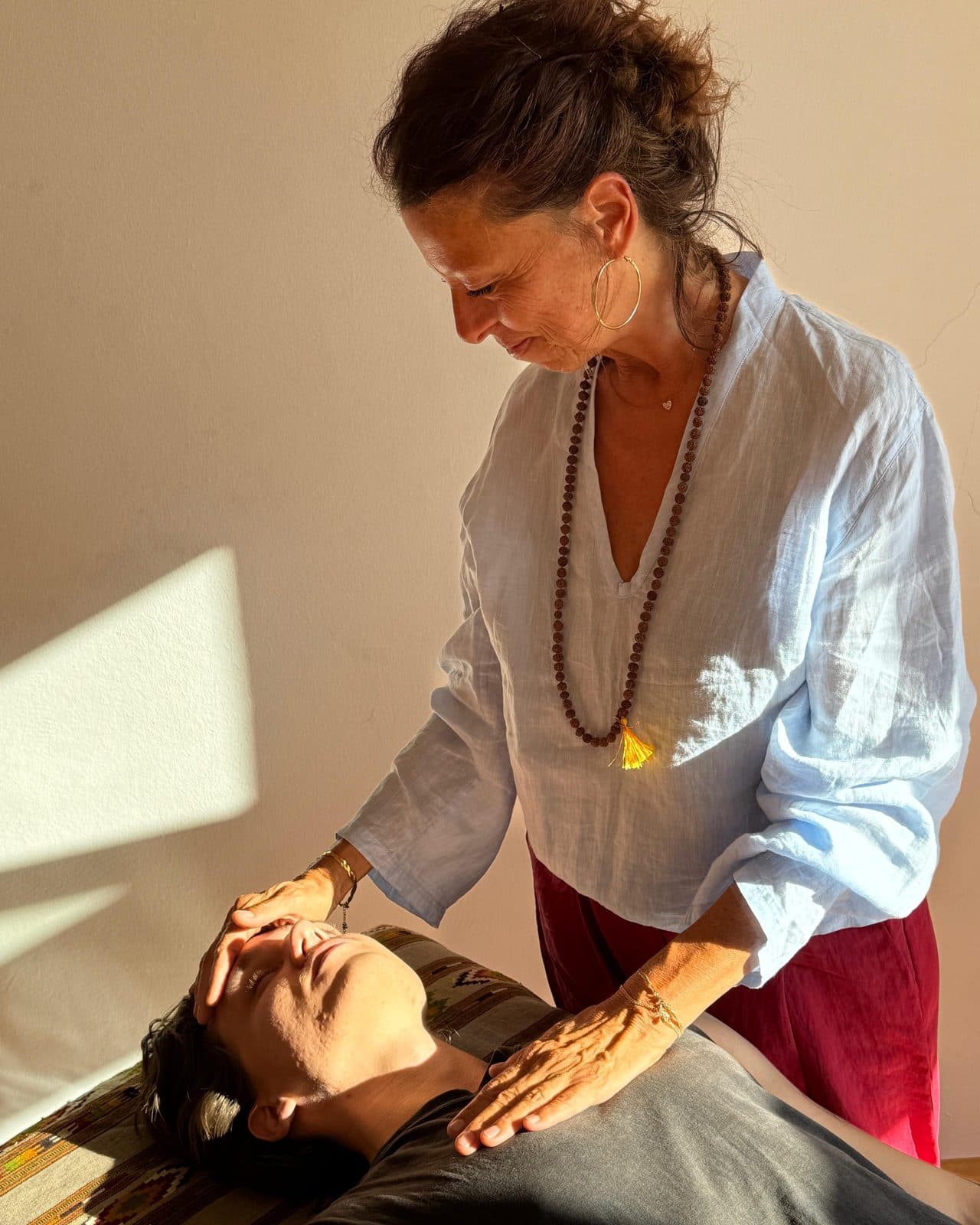 Beatrix's hands resting on a client's forehead and chest