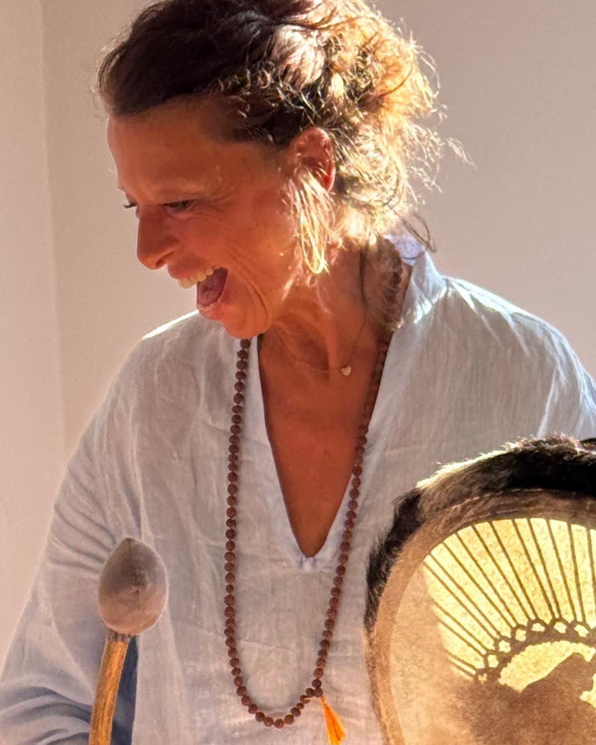 Beatrix laughing while holding a frame drum