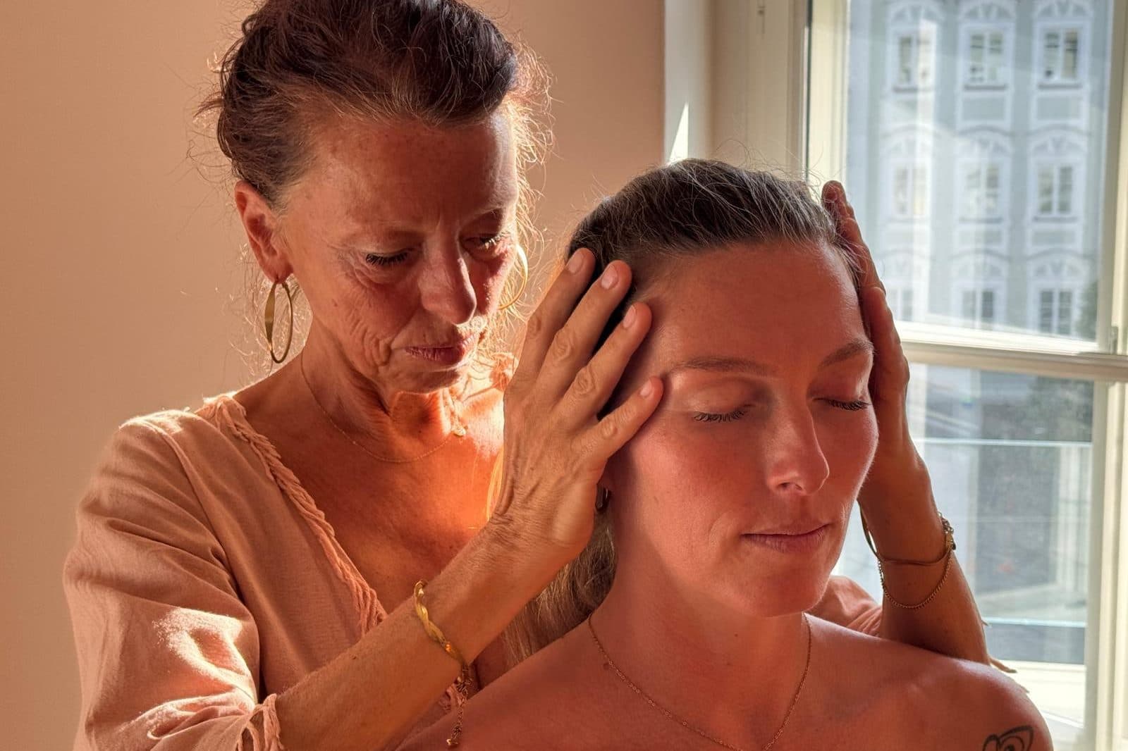 Hands cradling a client's head, a window in the background